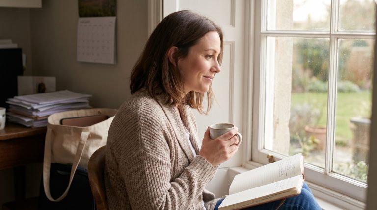 A woman resting quietly by a window with a peaceful expression during a busy season of life.