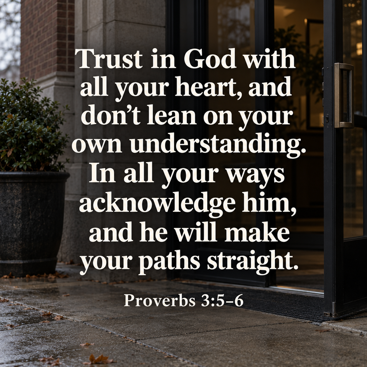 Large white text of Proverbs 3:5–6 over a photograph of an open glass door at a brick building entrance.